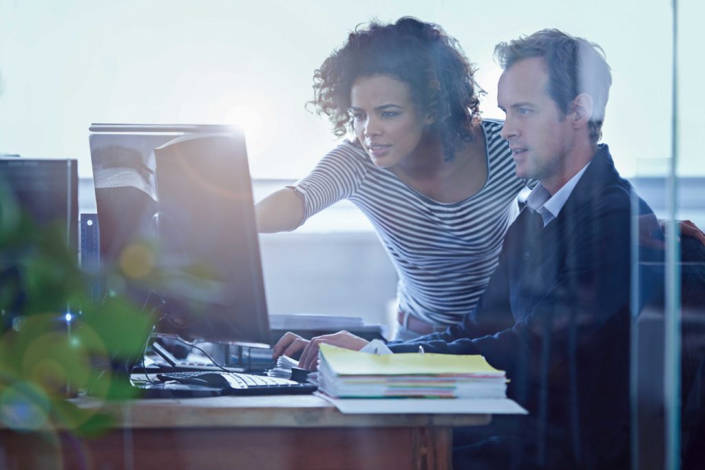 dos personas mirando la pantalla de una computadora compartida